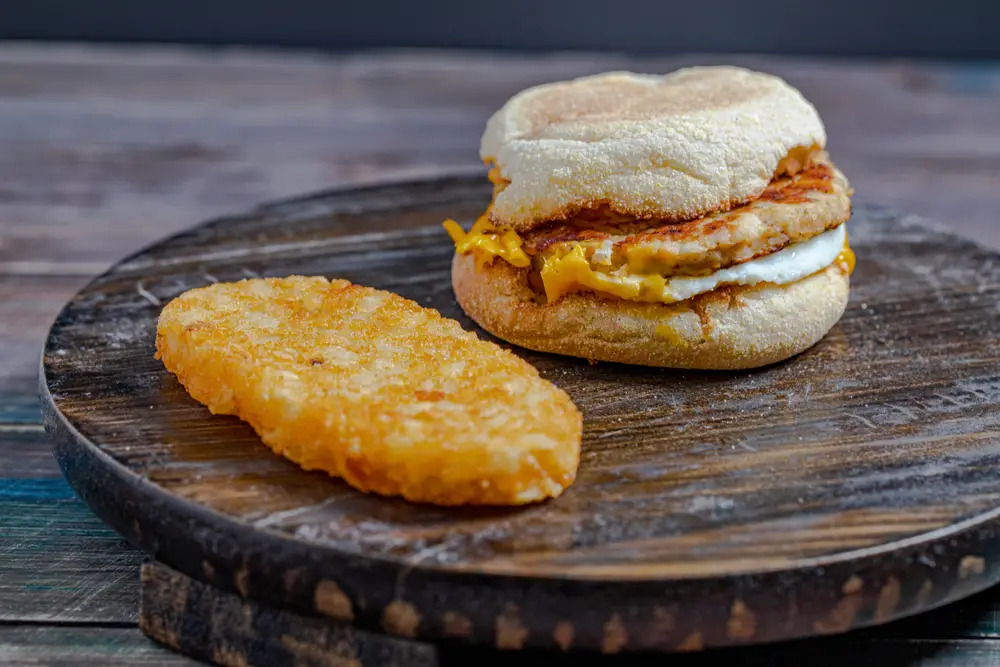 McDonald's sausage McMuffin and hash brown on wooden table