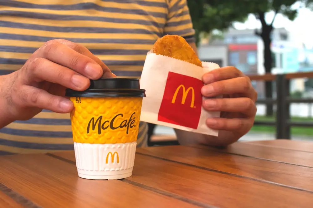 Person holding McDonald's coffee and hashbrown