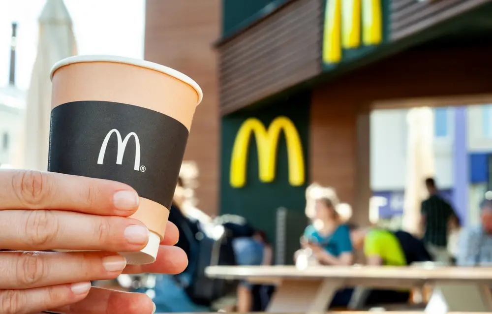 Person holding McDonald's coffee cup on restaurant patio
